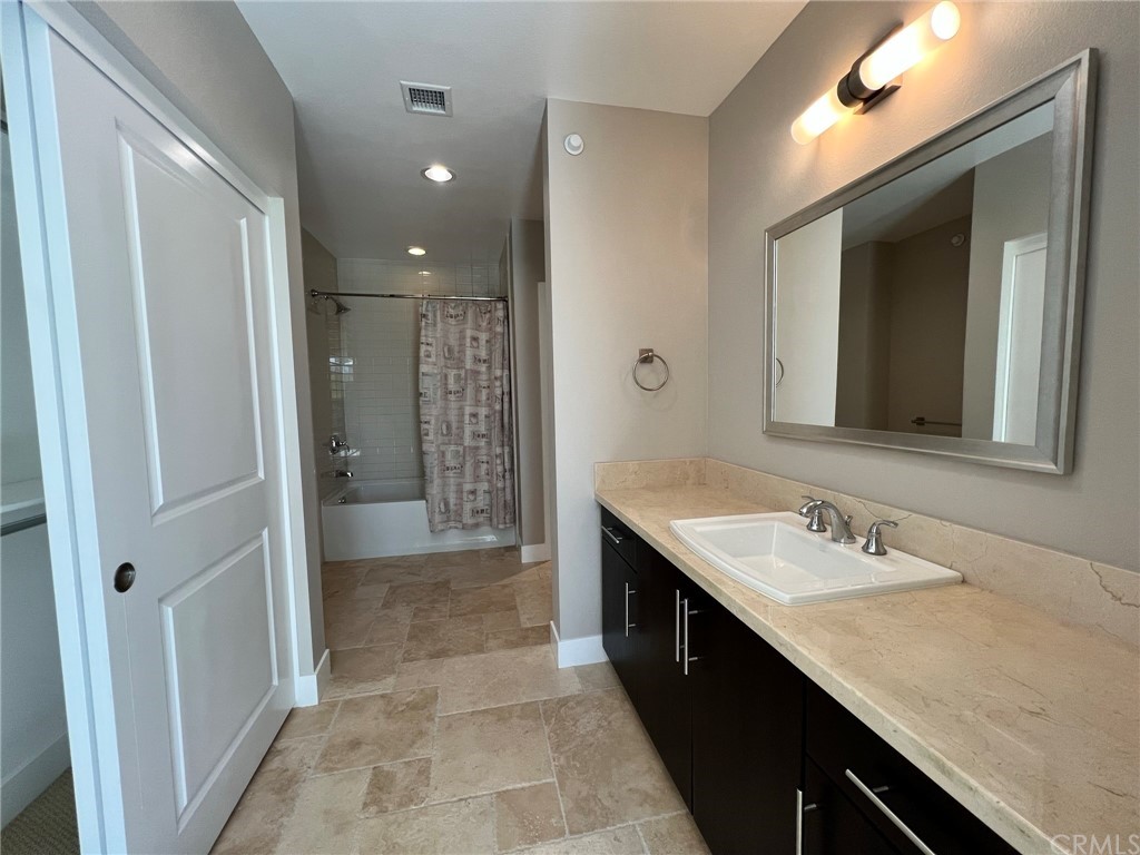 402 Rockefeller, Unit 212 Irvine, CA 92612 - Photo 19 of 27 a bathroom with a granite countertop sink a mirror and a shower