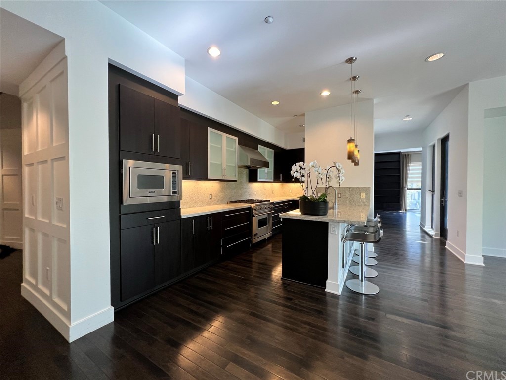 402 Rockefeller, Unit 212 Irvine, CA 92612 - Photo 10 of 27 a kitchen with stainless steel appliances kitchen island granite countertop a refrigerator a sink dishwasher and a stove with wooden floor
