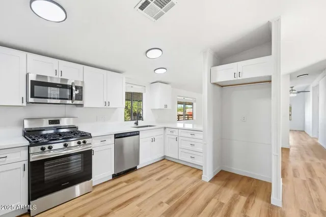 a kitchen with granite countertop a sink cabinets and stainless steel appliances