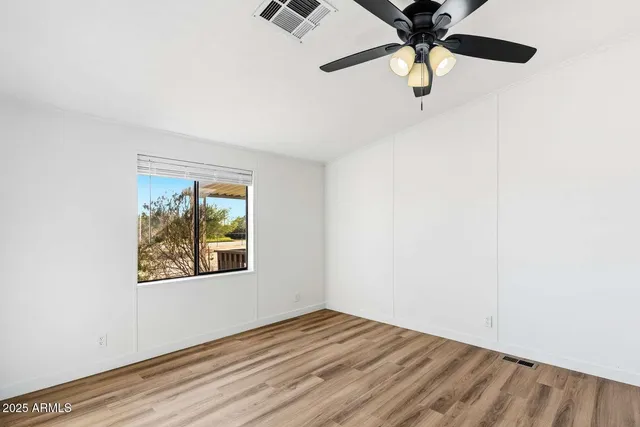 an empty room with wooden floor fan and windows