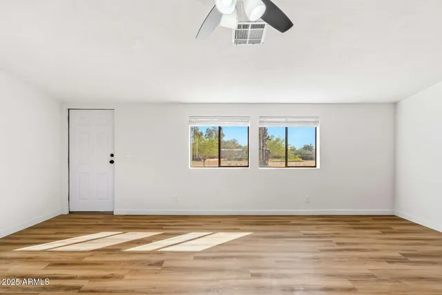 a view of an empty room with window and wooden floor