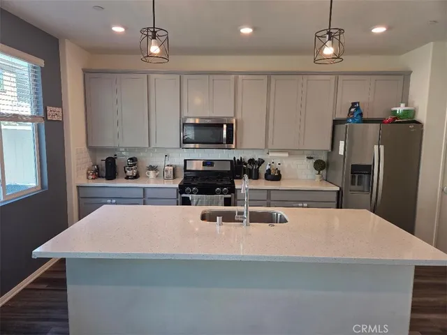 a kitchen with stainless steel appliances a stove a refrigerator a sink and a center island