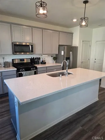 a kitchen with kitchen island a sink dishwasher a stove and a refrigerator with wooden floor