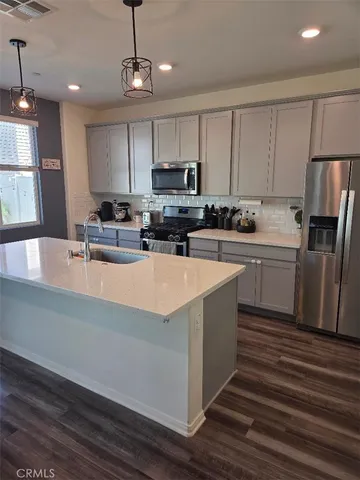 a kitchen with stainless steel appliances a sink a stove a refrigerator cabinets and a center island