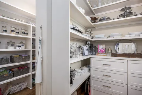 a kitchen with stainless steel appliances kitchen island granite countertop a table chairs wooden floors and white cabinets