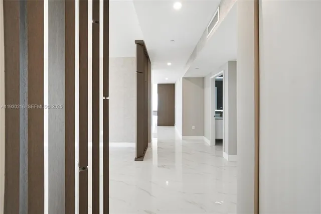 a view of a hallway with wooden floor and a living room