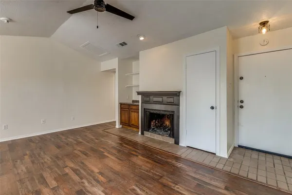 a view of an empty room with wooden floor fireplace and a window