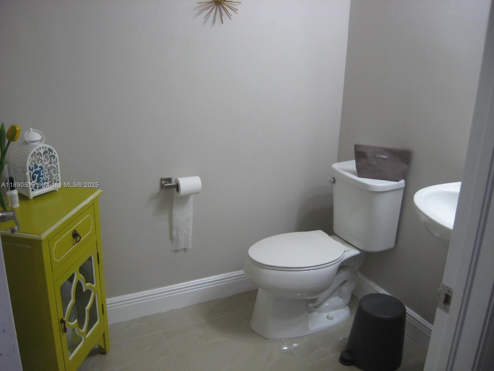 15070 Southwest 117th Way Miami, FL 33196 - Photo 11 of 14 a white toilet sitting next to a bathroom sink and a vanity