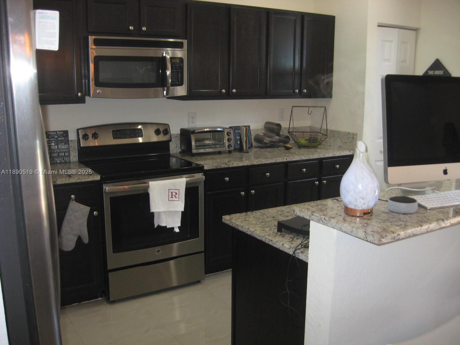 15070 Southwest 117th Way Miami, FL 33196 - Photo 6 of 14 a kitchen with stainless steel appliances granite countertop a stove microwave and refrigerator