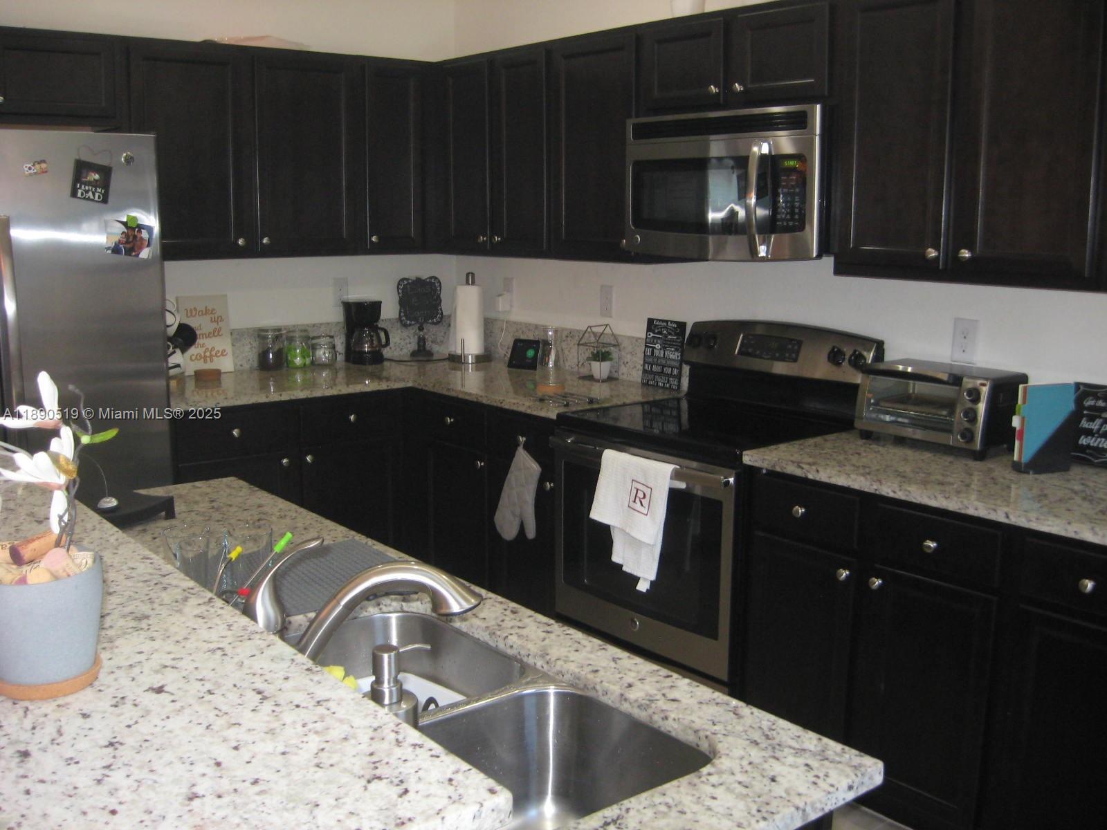 15070 Southwest 117th Way Miami, FL 33196 - Photo 7 of 14 a kitchen with granite countertop a sink a stove and cabinets