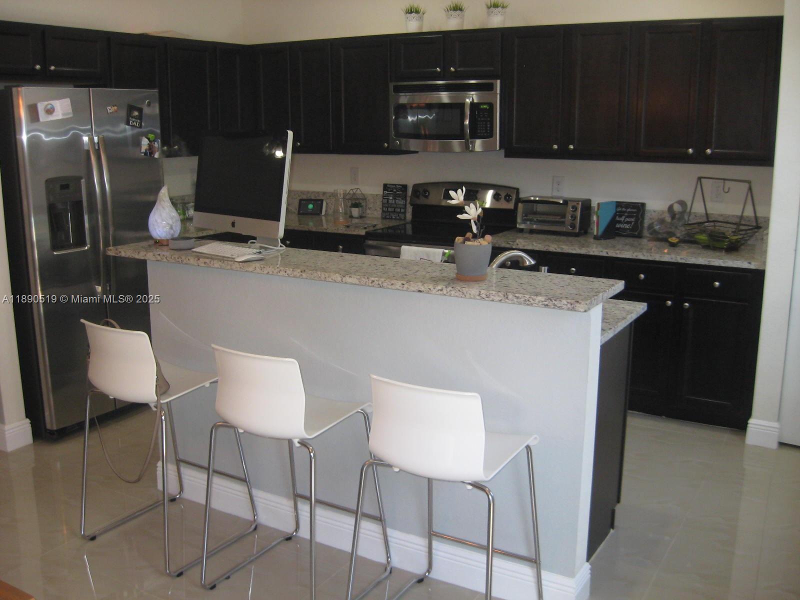 15070 Southwest 117th Way Miami, FL 33196 - Photo 10 of 14 a kitchen with stainless steel appliances granite countertop a sink refrigerator and cabinets