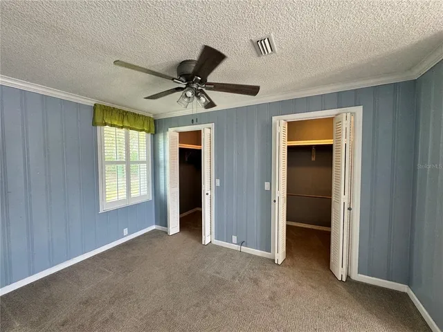 a view of a livingroom with a chandelier fan and windows
