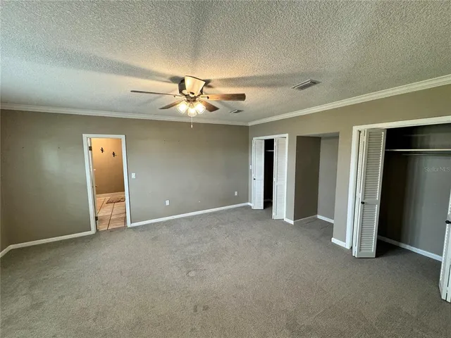 an empty room with closet and a ceiling fan