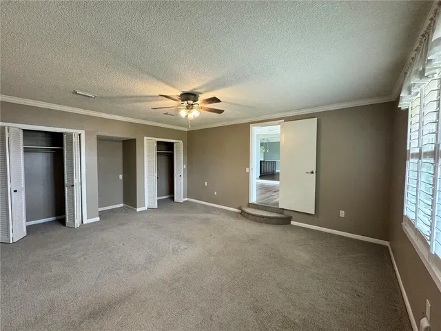an empty room with windows and chandelier fan