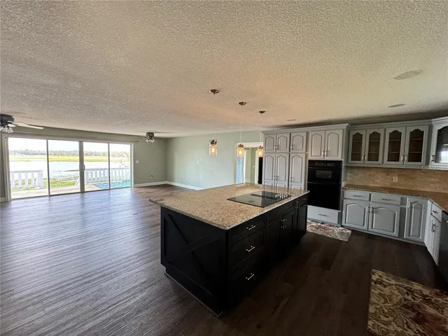 a kitchen with stainless steel appliances granite countertop a stove and a wooden floors