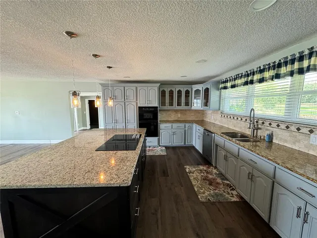 a large kitchen with granite countertop a sink and cabinets