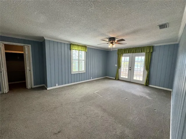 an empty room with windows and chandelier fan