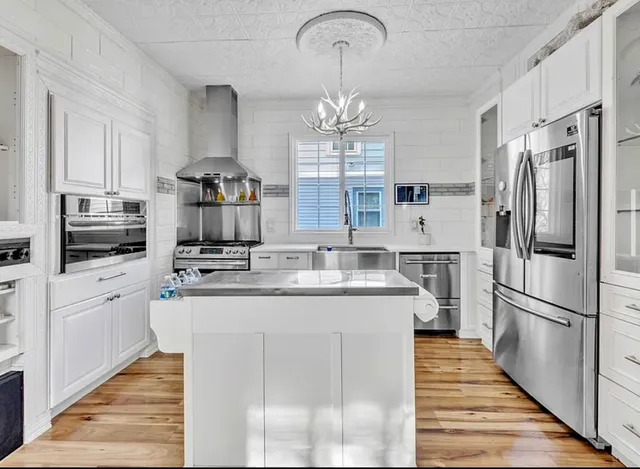 a kitchen with stainless steel appliances granite countertop a sink refrigerator and cabinets