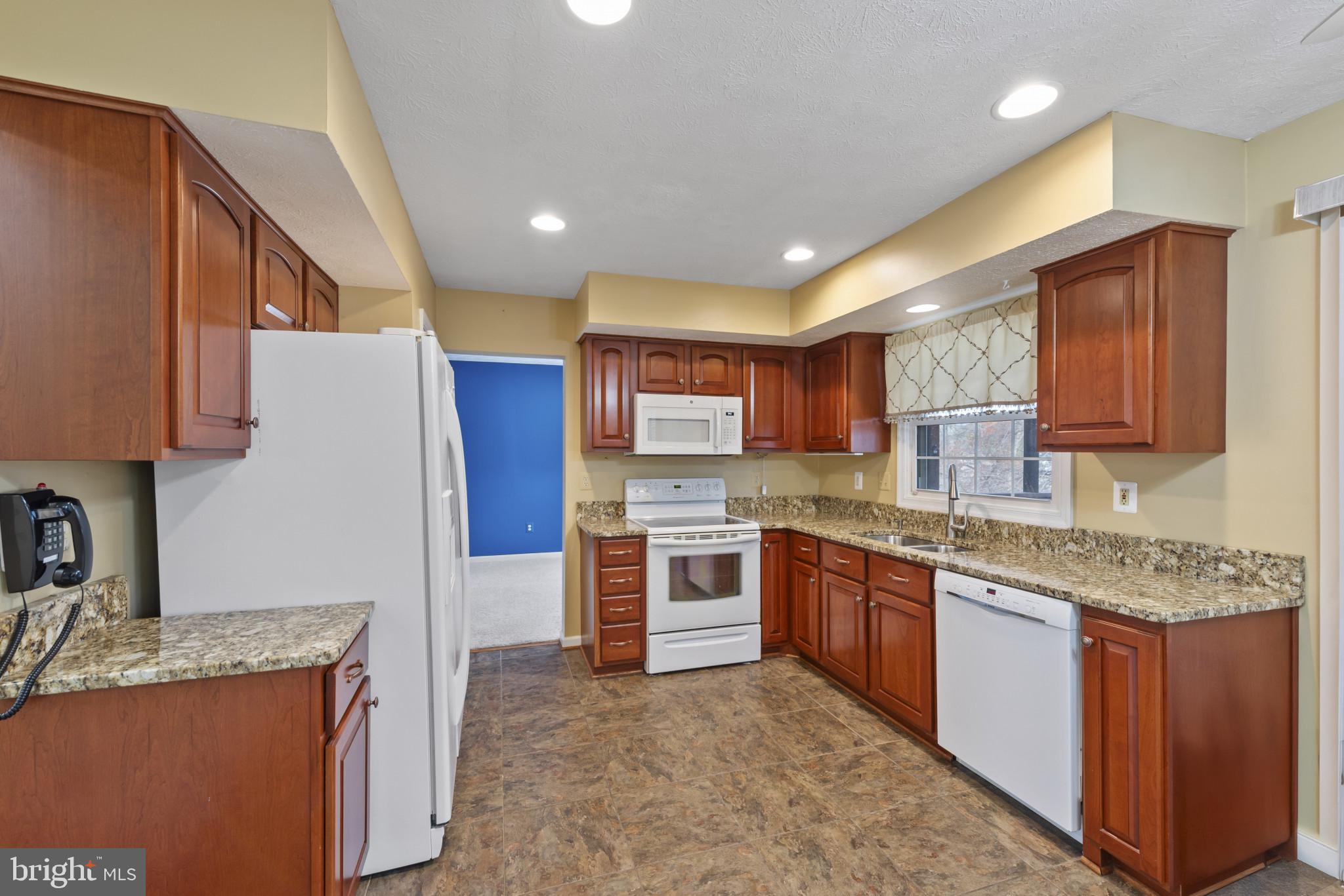 452 Doe Meadow Drive Owings Mills, MD 21117 - Photo 5 of 34 a kitchen with stainless steel appliances granite countertop a stove top oven a sink a refrigerator and white cabinets with wooden floor