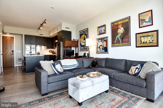 a living room with furniture kitchen view and a wooden floor