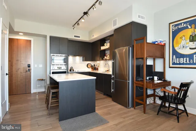 a kitchen with stainless steel appliances granite countertop a refrigerator a stove a sink a dining table and chairs with wooden floor