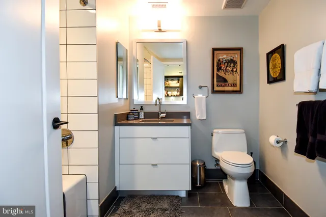 a bathroom with a granite countertop toilet sink and mirror