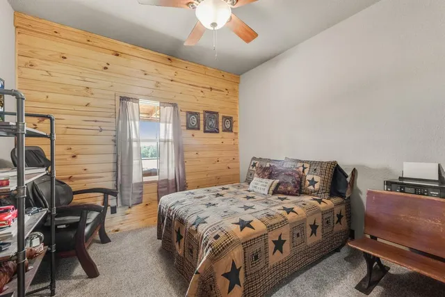 a bedroom with a bed a chair and potted plant on the dresser