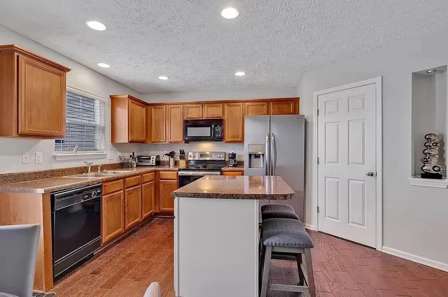 a kitchen with granite countertop a stove sink cabinets and refrigerator