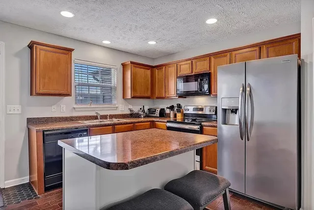 a kitchen with stainless steel appliances granite countertop a refrigerator a sink dishwasher a stove with wooden cabinets and a refrigerator