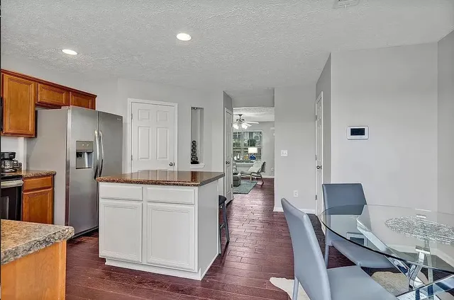 a kitchen with stainless steel appliances a dining table chairs and wooden floor