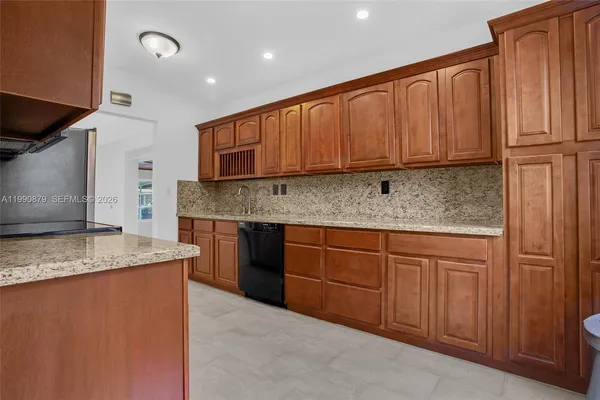 a kitchen with stainless steel appliances granite countertop wooden cabinets a refrigerator and a sink
