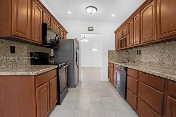 a kitchen with stainless steel appliances granite countertop a sink a stove and a refrigerator
