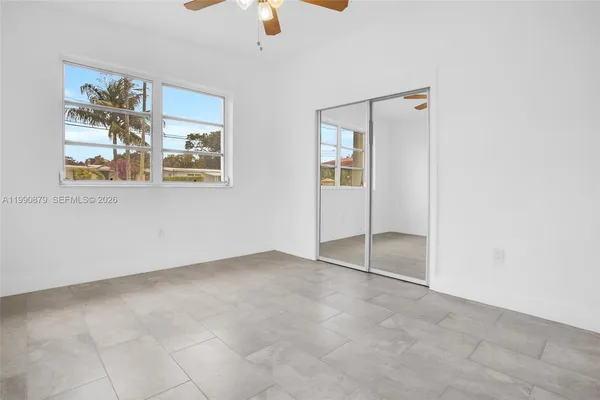 an empty room with ceiling fan and window
