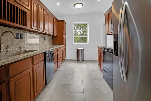 a kitchen with stainless steel appliances granite countertop a refrigerator a sink dishwasher a stove and a refrigerator
