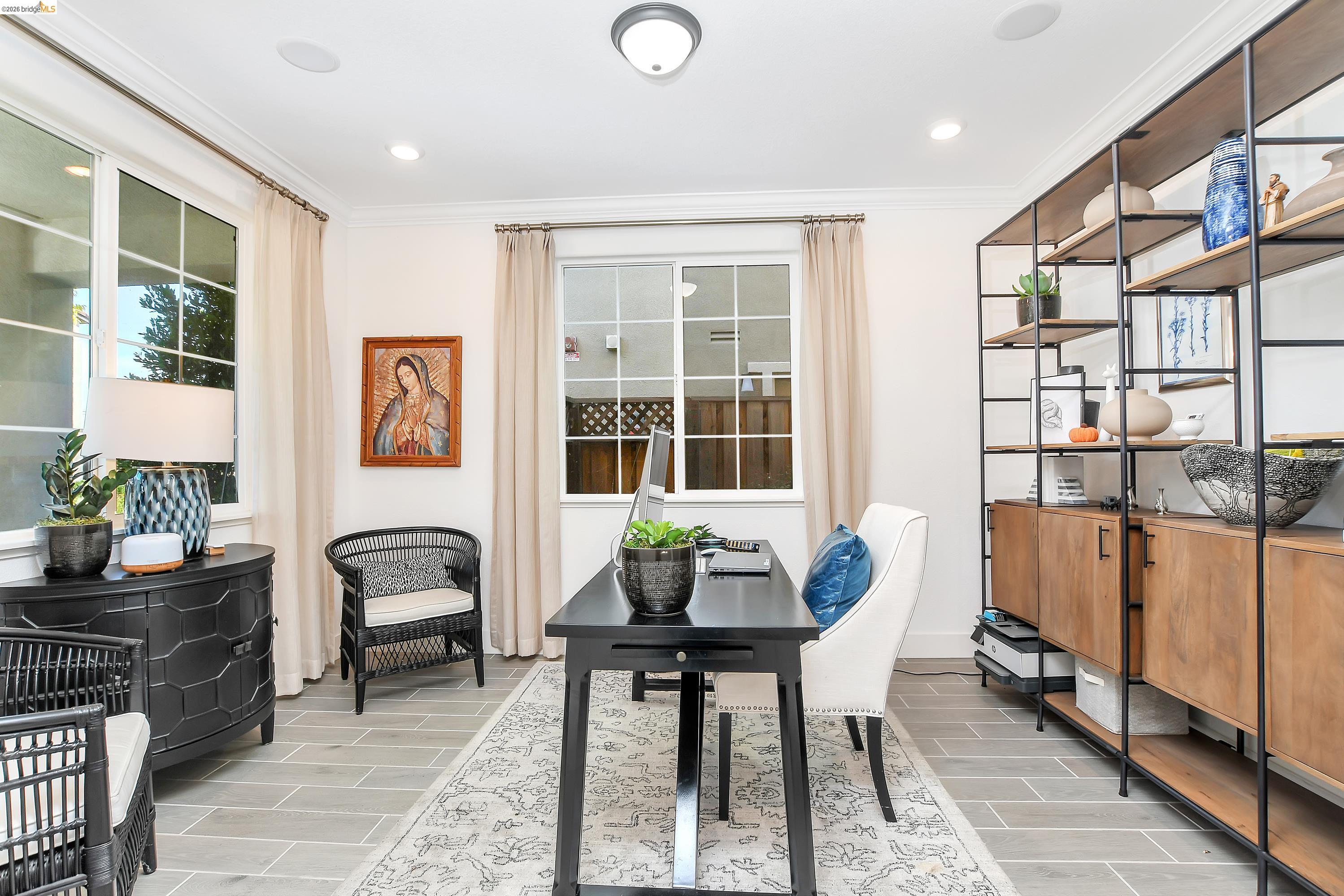 Tray ceiling with recessed lighting, crown molding, wood-finish flooring, multiple windows, and a built-in shelving unit with wood-finish cabinetry