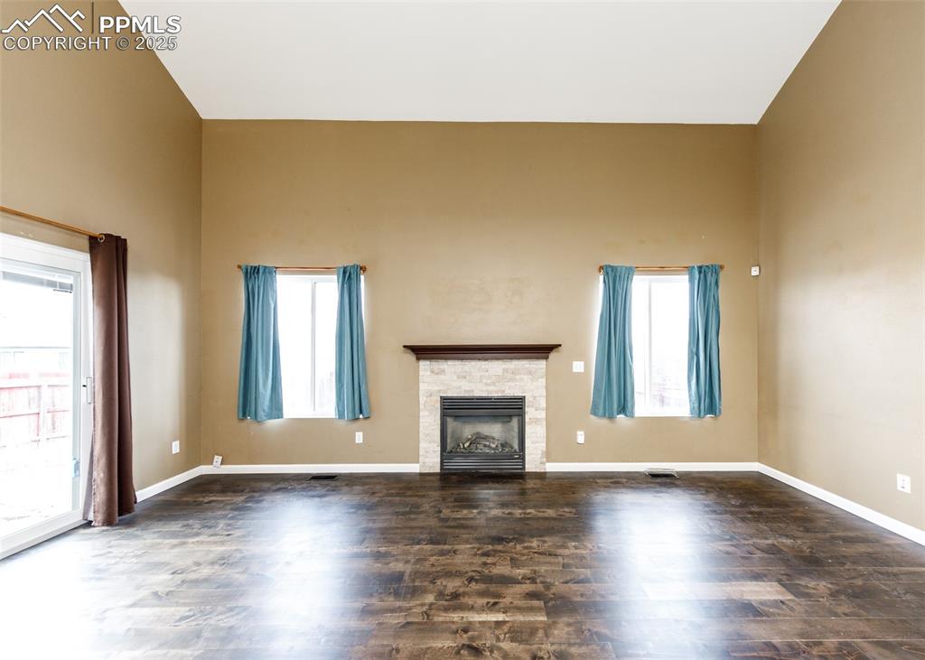 8119 Oliver Road Peyton, CO 80831 - Photo 12 of 38 an empty room with wooden floor fireplace and windows