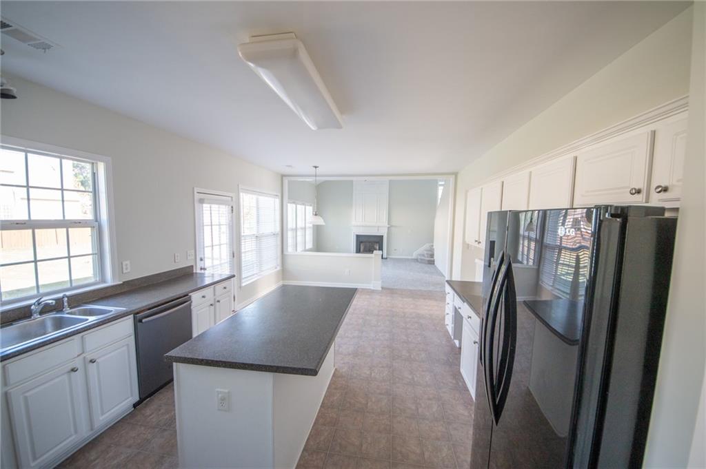 8145 Lockslay Way Suwanee, GA 30024 - Photo 6 of 18 a large kitchen with a refrigerator a sink dishwasher a stove and white cabinets with wooden floor