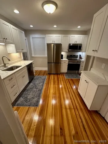 an open kitchen with kitchen island white cabinets and stainless steel appliances