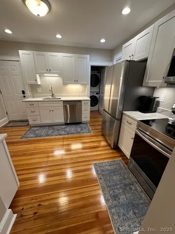 a large kitchen with stainless steel appliances wooden floor and a refrigerator