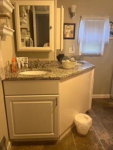 a bathroom with a granite countertop sink and a mirror