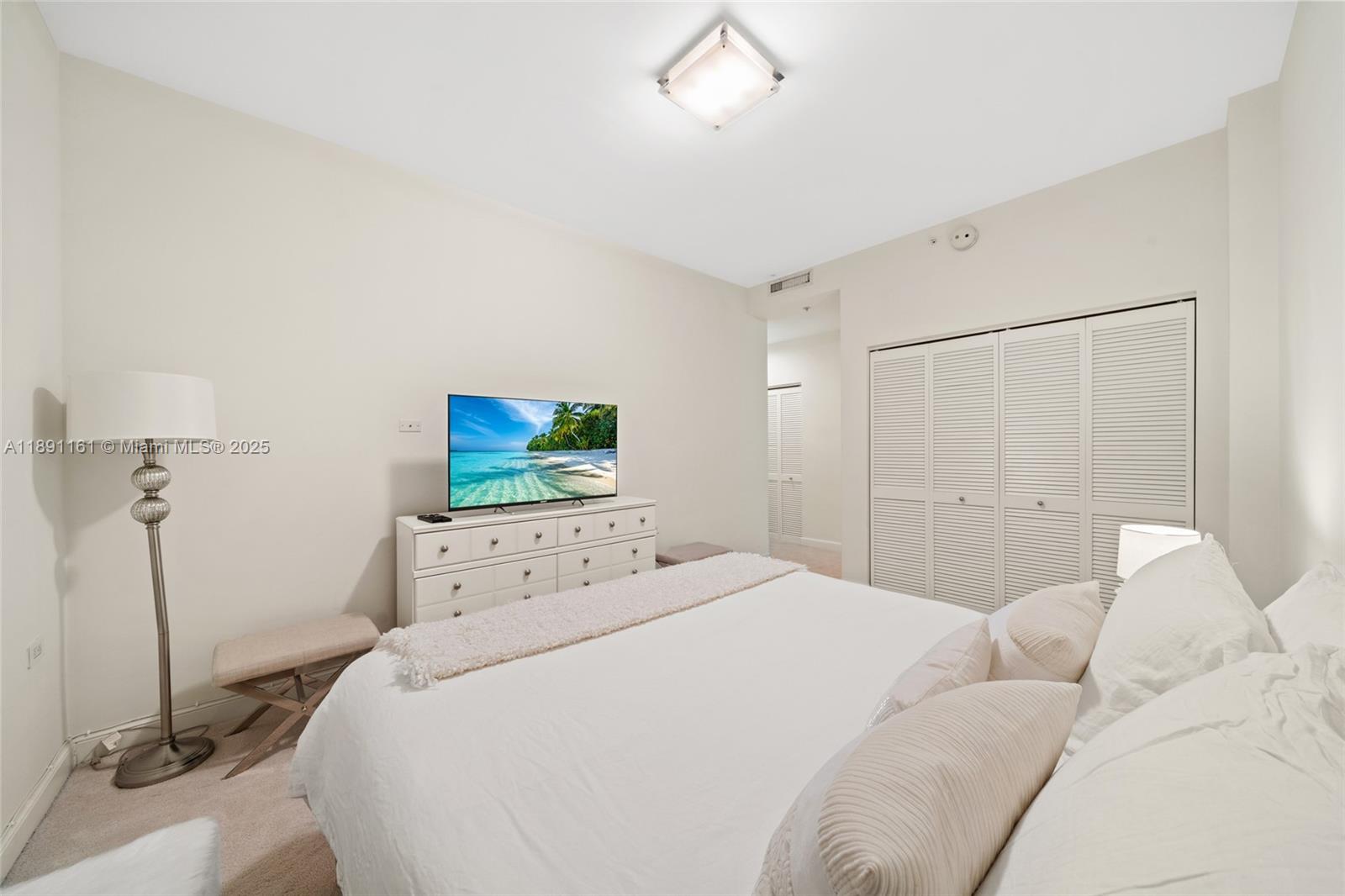 848 Brickell Key Drive, Unit 201 Miami, FL 33131 - Photo 26 of 31 a bedroom with a bed and a flat tv screen