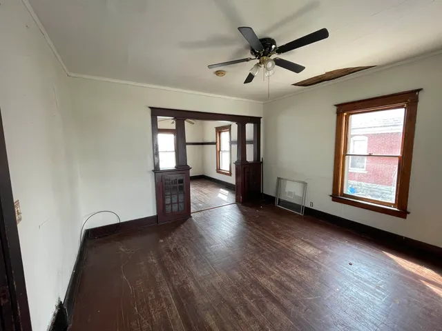 a view of empty room with wooden floor and fan