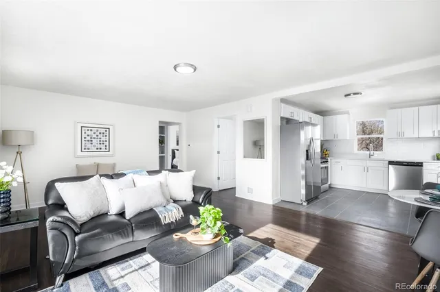 a living room with furniture white walls and kitchen view