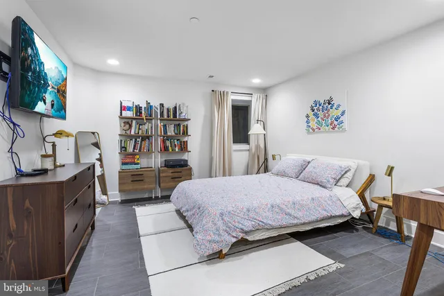 a bedroom with a large bed a flat screen tv and a book shelf