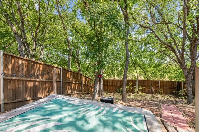 a view of backyard with wooden fence and a large tree