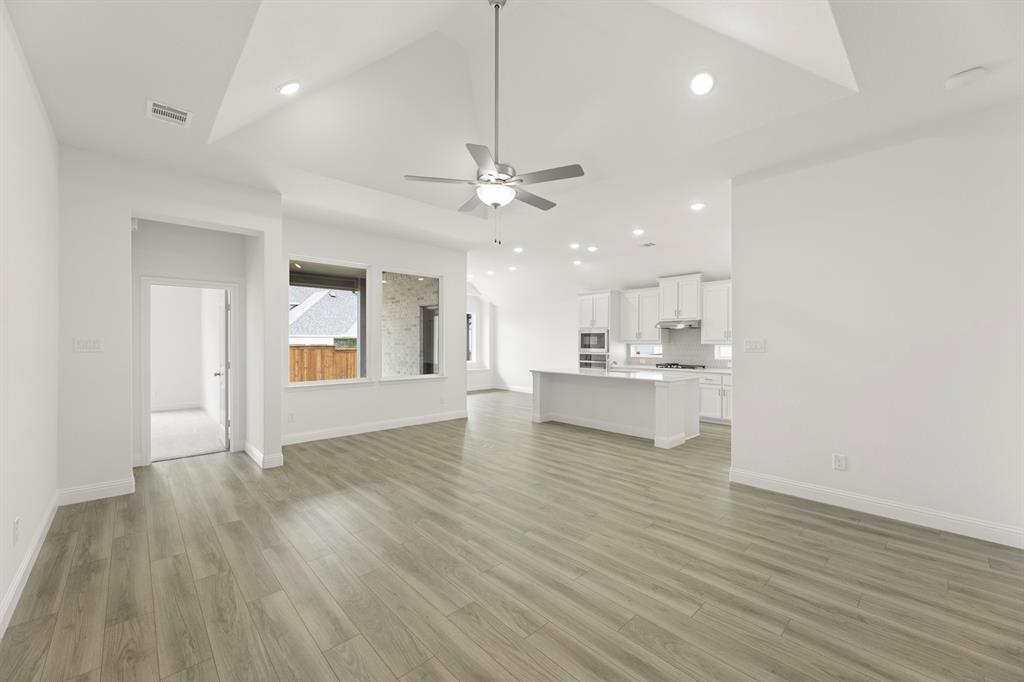 14551 Elion Court Pilot Point, TX 76258 - Photo 3 of 23 a view of an empty room and kitchen with wooden floor