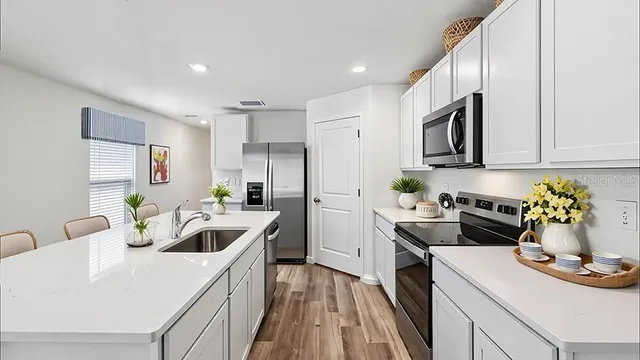 a kitchen that has a lot of cabinets a sink and appliances in it