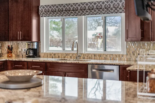 a view of a kitchen with granite countertop a sink stainless steel appliances and cabinets