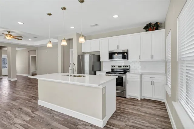 a kitchen with kitchen island a white counter top space stainless steel appliances and cabinets