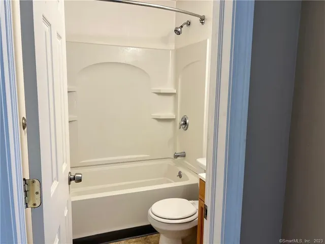a bathroom with a shower a toilet and a tub